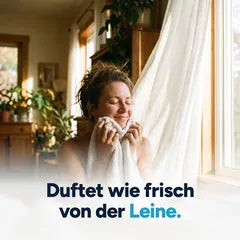 Frau drückt ihr Gesicht in ein frisch gewaschenes weißes Handtuch: Duftet wie frisch von der Leine